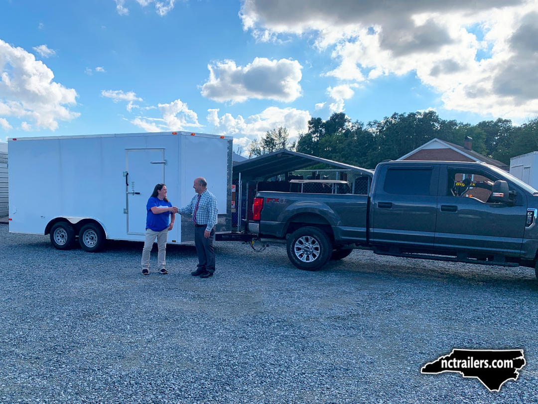 NC Trailers team member shaking hands with a customer taking delivery of a new enclosed trailer