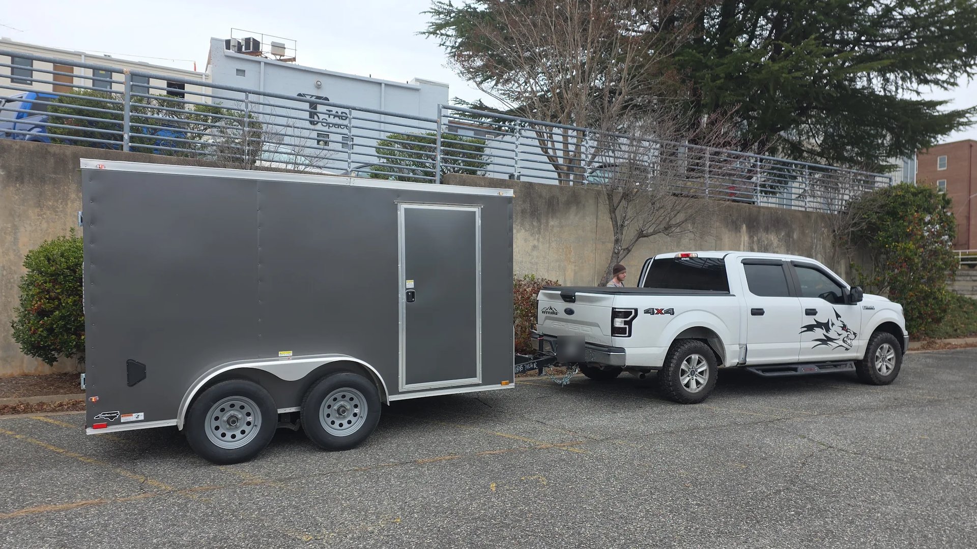 Charcoal tandem axle enclosed trailer hooked to a pickup with safety chains crossed, ready to tow