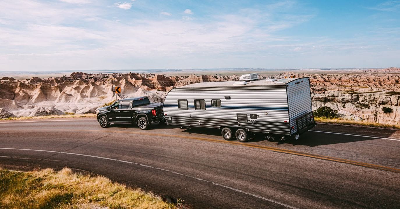 Travel trailer camper in tow behind a pickup truck