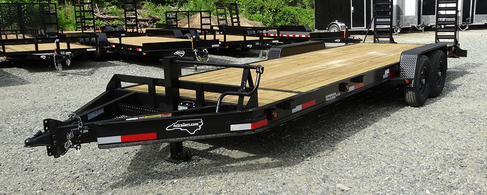 Superior 6x24 equipment trailer on the NC Trailers lot with an empty flat 2 inch treated wood deck, the kind of flat deck a tiny home gets built on