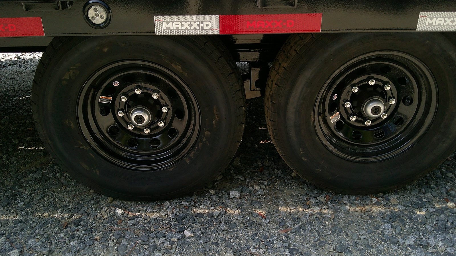 Tandem 7,000 lb axles on an NC Trailers equipment trailer, chrome grease-type dust caps on each hub