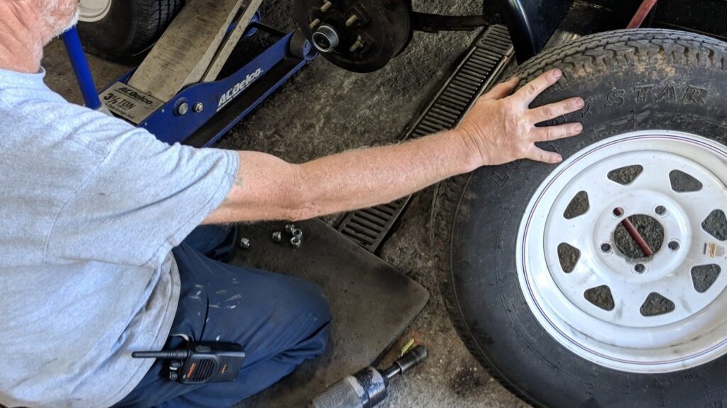 Service tech checking a trailer wheel and axle